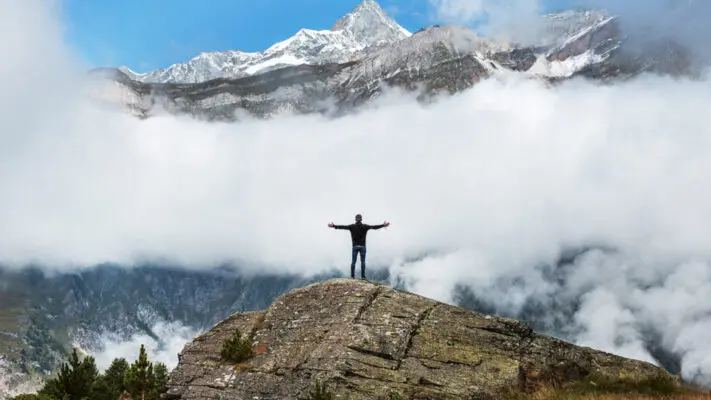 A person standing on top of a mountain with arms outstretched.