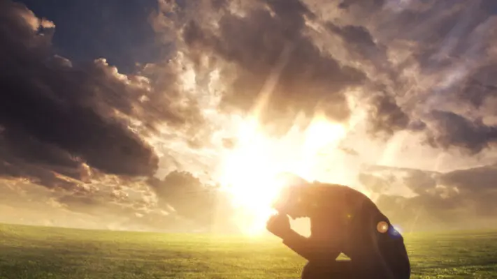 A person sitting in the grass with their head down.